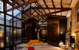 Living space with exposed timber beams, large glass walls, and industrial design elements.