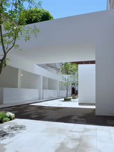 A modern pavilion with concrete walls and a glass roof, featuring a woman standing under an overhang.