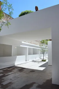 This image features a modern architectural design with a concrete walkway and minimalist white walls.