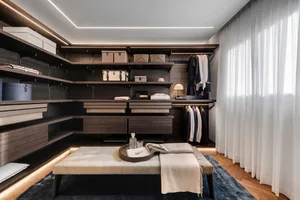 Modern closet with brown wooden shelves, drawers, and hanging garments