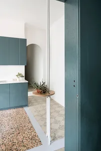 Modern kitchen with teal cabinets and terrazzo flooring.