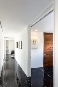 Modern minimalist hallway featuring black marble flooring and white walls.
