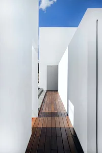 A minimalist white courtyard with wooden flooring and walls.