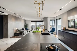 A modern residential kitchen featuring concrete flooring and a marble countertop.