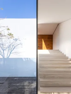 Staircase with glass walls, white walls, and wood floor, leading to a wooden door.
