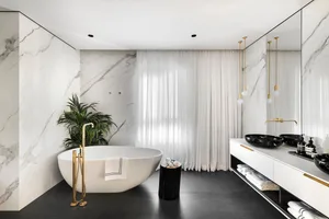 A minimalist bathroom featuring a freestanding bathtub, marble walls, and black accents.