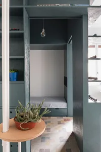 Minimalist bedroom with concrete walls, wooden floor, and bed.