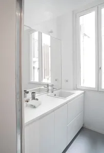 Modern minimalist bathroom with white composite cabinets and sink, featuring a large window and clear countertops.