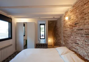 Modern bedroom with white furniture and brick accent wall.