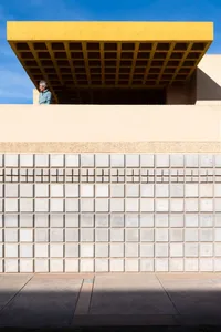 A modern building with a concrete facade and a yellow geometric overhead structure.