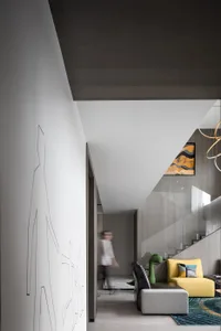 Modern living room with a minimalist design featuring a concrete floor and walls, accented by a colorful sofa and abstract wa