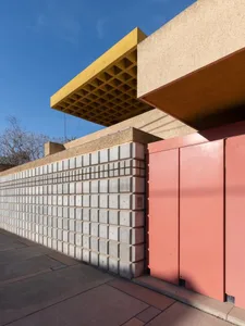 A modern building facade featuring a concrete wall and a red door.