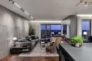 Modern living room with concrete wall, grey sofa, and potted plant