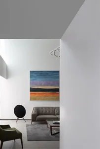 Modern living room with a large abstract painting, leather sofa, and round black speaker.