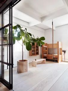 Industrial-style interior featuring a wooden swing bed suspended by a rope and a large fiddle leaf fig plant.