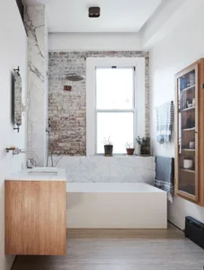 A modern bathroom with marble, brick, and wood elements.