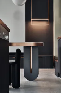 Modern minimalist dining room with a metal table and black chairs.