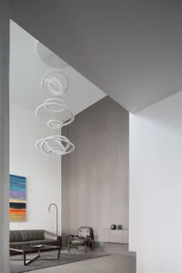 A modern minimalist living room with a sofa, armchair, coffee table, and abstract art on the wall.