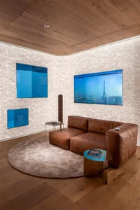 Contemporary living room featuring a brown leather sectional sofa, round rug, and large abstract wall art