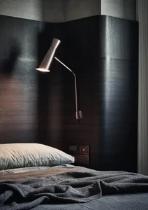 Minimalist bedroom with a textured fabric bedspread and a wall-mounted lamp.