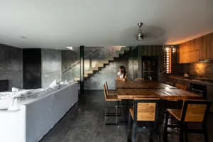 Industrial-style kitchen with concrete walls and a wooden dining table.