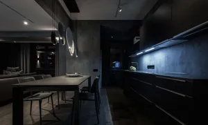 A modern residential kitchen with concrete walls and a black dining table with chairs.
