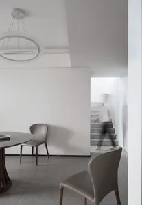 Modern minimalist dining room with concrete elements and a round marble table.