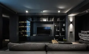 A modern black living room with concrete accents and dark furnishings.