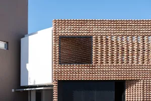 A modern building exterior featuring a brick facade with geometric patterns and a large window.