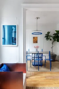 A modern dining room featuring a metal table and blue chairs.