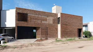 A modern house with a brick exterior featuring large windows and a concrete roof.