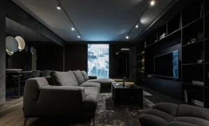 Industrial living room with concrete walls and floor, featuring a large sectional sofa, a coffee table with a laptop and an a