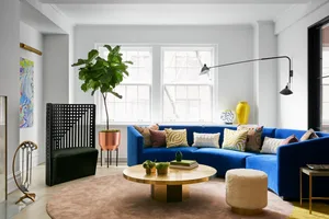 A modern living room with a blue curved sofa, round wooden coffee table, and decorative elements.