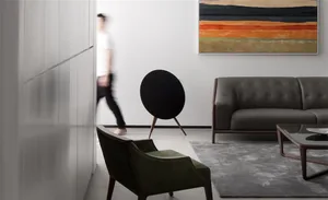 A modern living room featuring a leather sofa, green armchair, and abstract painting.