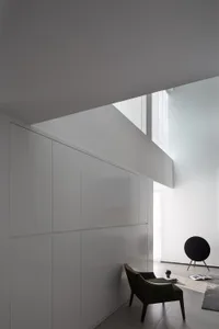 Modern, white, concrete interior space with minimalist design and green armchair.