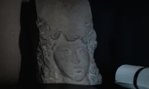 Detail of an ancient stone sculpture profile with a dark background and a light source on the right side.