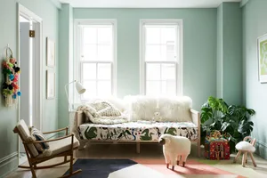A children's bedroom featuring textiles, cushions, plants, and a wooden frame