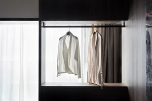 White blouses hanging on a clothing rack in a minimalist interior design setting.