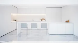 A minimalist white marble kitchen interior with sleek, modern cabinets and a long island.