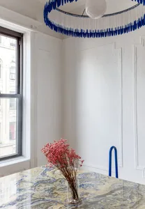 A modern interior featuring a marble table with pink flowers in a vase