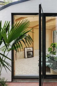 A modern interior featuring a living space with a terrazzo floor, framed pictures, and green plants.