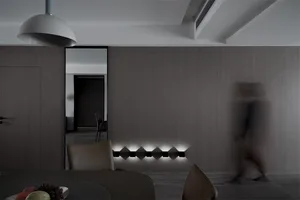 A modern minimalist residential interior with wood walls, a dining table, and warm lighting.