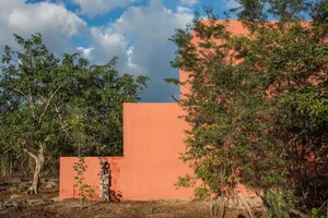 A modern residential exterior featuring textured brick walls and lush green foliage.