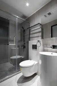 Modern, minimalist bathroom with concrete walls, white fixtures, and glass shower enclosure.