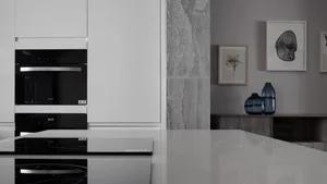Modern kitchen with marble countertops and sleek, white cabinets.