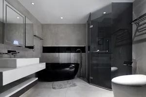 Modern minimalist bathroom with concrete walls, a black bathtub, and a white toilet.
