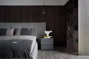 A modern minimalist bedroom featuring wood-paneled walls, a grey upholstered bed, and a grey wooden nightstand with books and