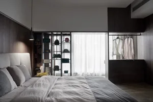 A modern bedroom featuring a bed with a neutral-colored bedspread and pillows, alongside shelves and dressers adorned with ba