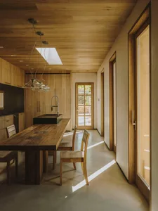Industrial-style kitchen featuring a wooden dining table and chairs, with a skylight and large windows allowing natural light