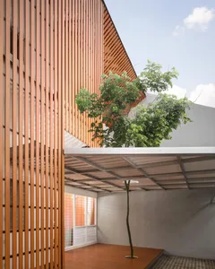 A modern exterior featuring wooden paneling and a large tree in the courtyard.
